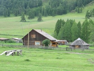 Une maison et une yourte en bois à sa droite comme si souvent dans la République de l’Altaï.